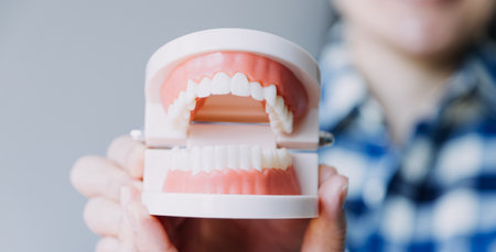 Stomatology concept, partial portrait of girl with strong white teeth looking at camera and smiling, fingers near face. Closeup of young woman at dentist's, studio, indoorsの写真素材