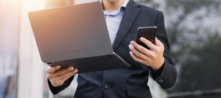 Asian business man and young beautiful woman working on digital tablet computer standing outside office building.の写真素材
