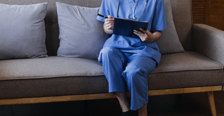 Homecare nursing service and elderly people cardiology healthcare. Close up of young hispanic female doctor nurse check mature caucasian man patient heartbeat using stethoscope during visitの写真素材