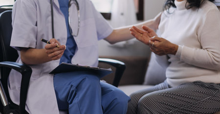 Homecare nursing service and elderly people cardiology healthcare. Close up of young hispanic female doctor nurse check mature caucasian man patient heartbeat using stethoscope during visitの写真素材