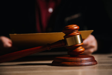 Justice and law concept.Male judge in a courtroom with the gavel, working with, computer and docking keyboard, eyeglasses, on table in morning lightの写真素材