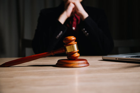 Justice and law concept.Male judge in a courtroom with the gavel, working with, computer and docking keyboard, eyeglasses, on table in morning lightの写真素材