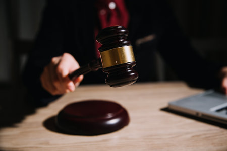 Justice and law concept.Male judge in a courtroom with the gavel, working with, computer and docking keyboard, eyeglasses, on table in morning lightの写真素材