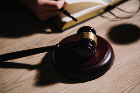 Justice and law concept.Male judge in a courtroom with the gavel, working with, computer and docking keyboard, eyeglasses, on table in morning lightの写真素材