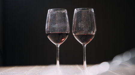 Set of hands holding red wine glass isolated on black background.の写真素材