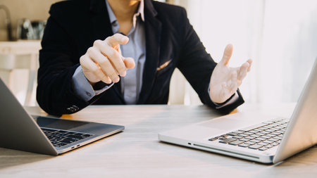 Mature businessman using a digital tablet to discuss information with a younger colleague in a modern business loungeの写真素材