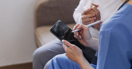 Homecare nursing service and elderly people cardiology healthcare. Close up of young hispanic female doctor nurse check mature caucasian man patient heartbeat using stethoscope during visitの写真素材