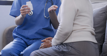 Homecare nursing service and elderly people cardiology healthcare. Close up of young hispanic female doctor nurse check mature caucasian man patient heartbeat using stethoscope during visitの写真素材