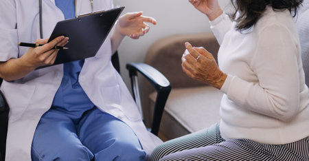 Homecare nursing service and elderly people cardiology healthcare. Close up of young hispanic female doctor nurse check mature caucasian man patient heartbeat using stethoscope during visitの写真素材