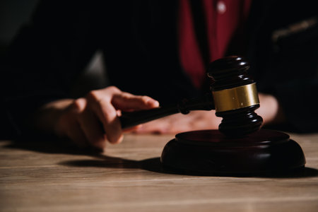 Justice and law concept.Male judge in a courtroom with the gavel, working with, computer and docking keyboard, eyeglasses, on table in morning lightの写真素材