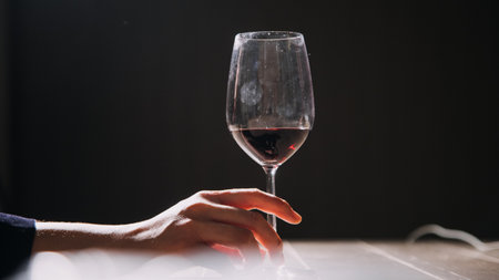 Set of hands holding red wine glass isolated on black background.