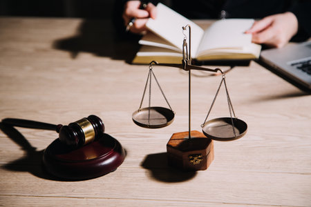 Justice and law concept.Male judge in a courtroom with the gavel, working with, computer and docking keyboard, eyeglasses, on table in morning lightの写真素材