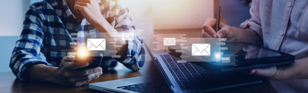 Businessman hands using Laptop typing on keyboard and surfing the internet on office table with email icon, email marketing concept, send e-mail or newsletter, online working internet network.の写真素材