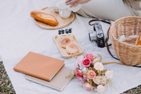 Young pretty brunette twin girls sitting on the grass with legs slightly bent in knees and looking in a brown book, wearing casual coat in autumn sunny weather on blurry background.の写真素材