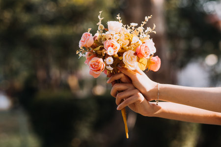 Young pretty brunette twin girls sitting on the grass with legs slightly bent in knees and looking in a brown book, wearing casual coat in autumn sunny weather on blurry background.の写真素材