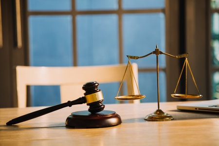 Justice and law concept.Male judge in a courtroom with the gavel, working with, computer and docking keyboard, eyeglasses, on table in morning lightの写真素材