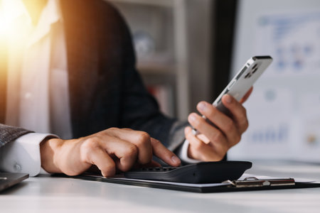 Asian Business woman using calculator and laptop for doing math finance on an office desk, tax, report, accounting, statistics, and analytical research conceptの写真素材