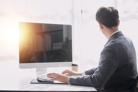 Asian Business woman using calculator and laptop for doing math finance on an office desk, tax, report, accounting, statistics, and analytical research conceptの写真素材