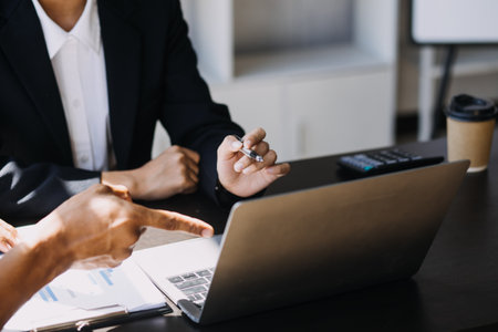 Asian Business woman using calculator and laptop for doing math finance on an office desk, tax, report, accounting, statistics, and analytical research conceptの写真素材