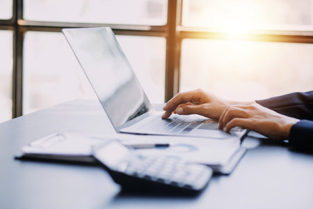 Asian Business woman using calculator and laptop for doing math finance on an office desk, tax, report, accounting, statistics, and analytical research conceptの写真素材