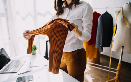 Beautiful lady blogger showing clothes in front of the camera to recording vlog video live streaming at her shop. Online Shopping Cart notion.の写真素材