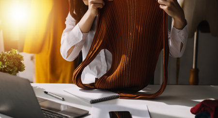 Fashion blogger concept, Young women selling clothes on video streaming.Startup small business SME, using smartphone or tablet taking receive and checking in studioの写真素材