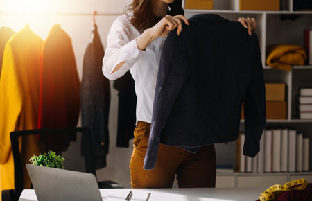 Fashion blogger concept, Young women selling clothes on video streaming.Startup small business SME, using smartphone or tablet taking receive and checking in studioの写真素材