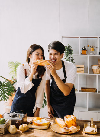 Image of newlywed couple cooking at home. Asia young couple cooking together with Bread and fruit in cozy kitchen in homeの写真素材