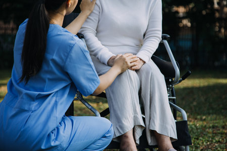 Asian young caregiver nurse support senior older male walking outdoors. Specialist girl doctor help and take care of elderly mature man patient doing physical therapy in public park at nursing home.の写真素材