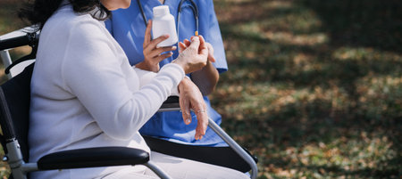 Asian young caregiver nurse support senior older male walking outdoors. Specialist girl doctor help and take care of elderly mature man patient doing physical therapy in public park at nursing home.の写真素材