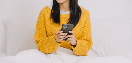 Efficient Young Millennial Girl Sitting on a Bed in the Morning, Uses Laptop Computer and Eats Croissants and Drinks Coffee for Breakfast. Top Down Shot.の写真素材