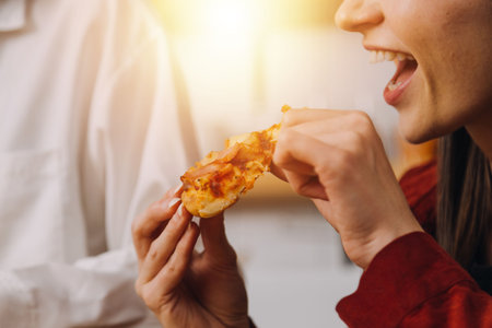 <p>Young woman eating pizza and laughing while sitting with her friends in a restaurant. Group of friends enjoying while having food and drinks at cafe.</p>の写真素材