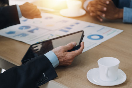 Financial analysts analyze business financial reports on a digital tablet planning investment project during a discussion at a meeting of corporate showing the results of their successful teamwork.の写真素材