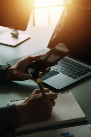 Attractive smiling young asian business woman work at home office, Asian woman working on laptop computer holding tablet.の写真素材