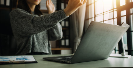 Attractive smiling young asian business woman work at home office, Asian woman working on laptop computer holding tablet.の写真素材