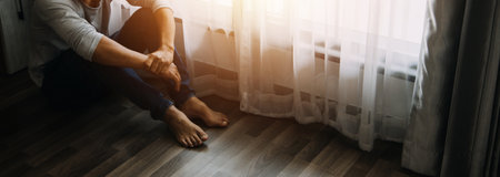 Alone man silhouette staring at the window closed with curtains in bedroom. Man stands at window aloneの写真素材