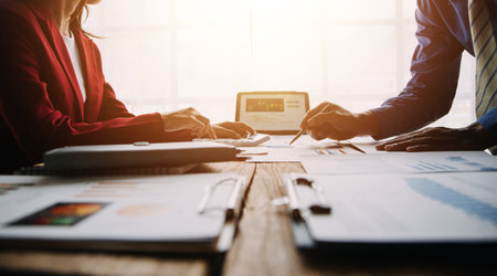 Financial analysts analyze business financial reports on a digital tablet planning investment project during a discussion at a meeting of corporate showing the results of their successful teamwork.の写真素材