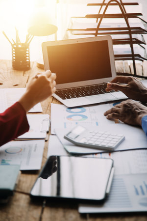 Financial analysts analyze business financial reports on a digital tablet planning investment project during a discussion at a meeting of corporate showing the results of their successful teamwork.の写真素材