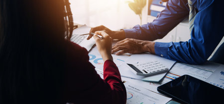 Group of confident business people point to graphs and charts to analyze market data, balance sheet, account, net profit to plan new sales strategies to increase production capacity.の写真素材