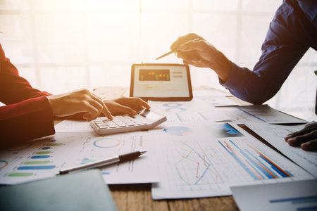 Group of confident business people point to graphs and charts to analyze market data, balance sheet, account, net profit to plan new sales strategies to increase production capacity.の写真素材