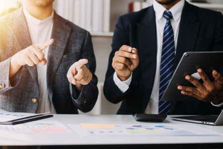 Financial analysts analyze business financial reports on a digital tablet planning investment project during a discussion at a meeting of corporate showing the results of their successful teamwork.の写真素材