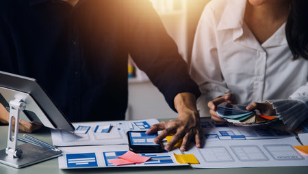 Close up ux developer and ui designer brainstorming about mobile app interface wireframe design on table with customer breif and color code at modern office.Creative digital development agencyの写真素材