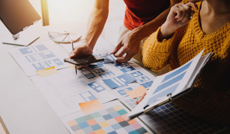 Close up ux developer and ui designer brainstorming about mobile app interface wireframe design on table with customer breif and color code at modern office.Creative digital development agencyの写真素材