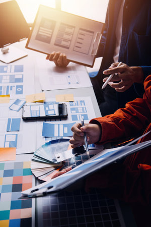 Close up ux developer and ui designer brainstorming about mobile app interface wireframe design on table with customer breif and color code at modern office.Creative digital development agencyの写真素材