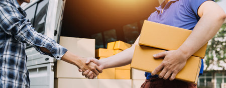 Delivery man with protective mask and gloves delivering parcels during lockdown and pandemic and holding mobile contactless payment machineの写真素材
