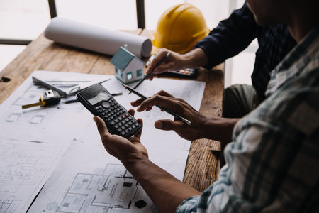 Construction and structure concept of engineer working drawing on blueprint meeting for project working with partner on model building and engineering tools in working site, construction conceptの写真素材