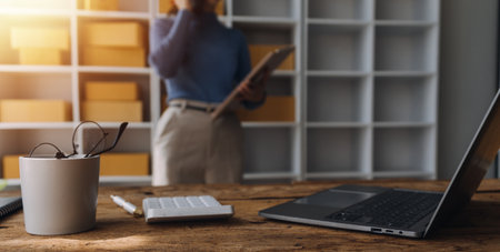 Startup SME small business entrepreneur of freelance Asian woman wearing apron using laptop and box to receive and review orders online to prepare to pack sell to customers, online sme business ideas.の写真素材