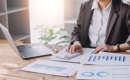 Businesswoman or accountant working Financial investment on calculator, calculate, analyze business and marketing growth on financial document data graph, Accounting, Economic, commercial concept.の写真素材