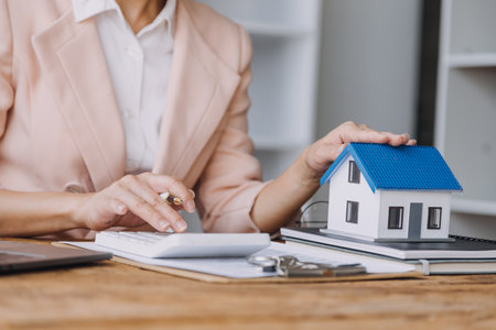 Real estate broker agent presenting and consult to customer to decision making sign insurance form agreement, buy and sell home model, concerning mortgage loan offer for and house insuranceの写真素材