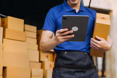 Asian business men use laptop computer checking customer order online shipping boxes at home. Starting Small business entrepreneur SME freelanceの写真素材